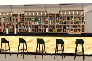 Innenansicht der Bar im Sunrise Queen Luxury Hotel mit Barhockern und einer großen Getränkewand.