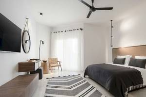 Ein modernes Hotelzimmer im Serry Beach Resort mit weißem Interieur, einem Bett, einem Fernseher und einer Deckenventilator.