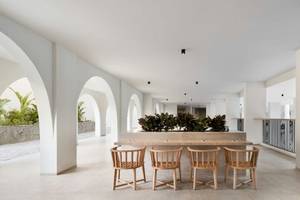 Innenbereich des Serry Beach Resort mit weißem Wanddesign, hölzernen Stühlen und Tischen, und grünen Pflanzen.