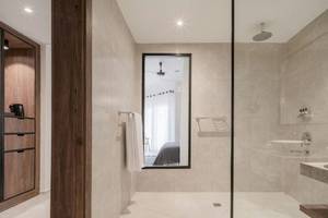 Ein modernes Badezimmer im Serry Beach Resort mit einer Duschkabine, einem Waschbecken, einem Spiegel und Holzmöbeln.