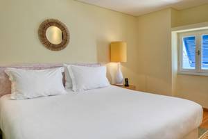 Schlafzimmer im Mykonos Theoxenia Boutique Hotel mit einem Bett, Lampen und Fenstern.