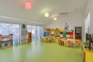 Kinderzimmer im Dobedan Exclusive Hotel & Spa Belek mit gelbem Boden, bunten Möbeln und Spielzeug.