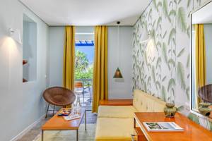 Wohnzimmer im Mykonos Theoxenia Boutique Hotel mit gelber Couch und blauem Tisch.