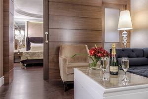 Innenansicht des Wohnbereichs des Dobedan Exclusive Hotel & Spa Belek mit einem Bett im Hintergrund.