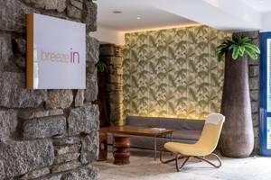 Der Eingangsbereich des Breeze in Hotels mit einem Sofa und einem Stuhl.