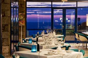 Das Innenrestaurant des Mykonos Theoxenia Boutique Hotels mit gedeckten Tischen und Blick auf den Abendhimmel.