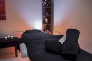 Massagebehandlungsliege im Hipotels Mediterraneo mit schwarzen Handtüchern und einer weißen Blume.