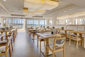 Innenansicht des Restaurants im Hipotels Mediterraneo mit freien Tischen und Blick auf den Strand.