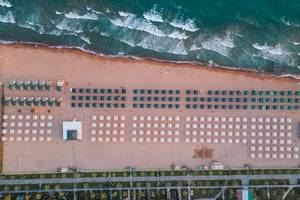 Luftaufnahme des Strandes des Sentido Kamelya Selin Hotels mit vielen Sonnenschirmen und Liegen