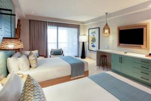 Doppelzimmer im Lopesan Costa Bavaro Resort mit zwei Betten, Fernseher, Schreibtisch und Schlafbereich.