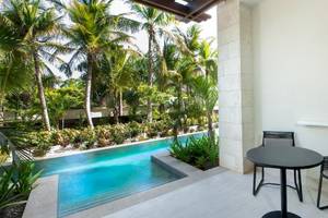 Terrasse mit Tisch und Sesseln vor einem Pool im Lopesan Costa Bavaro Resort Spa & Casino