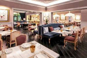 Innenansicht des Restaurants im Lopesan Costa Bavaro Resort Spa & Casino mit gedeckten Tischen und Stühlen.