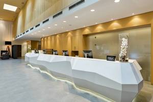 Lobby des DoubleTree by Hilton Vienna Schonbrunn mit Rezeptionstresen, Schreibtischen und Dekoration.