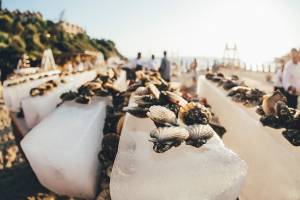 Ein Bild von Meeresfrüchten auf Eisblöcken, die am Strand von Club Marvy angeordnet sind, mit einigen Leuten im Hintergrund.