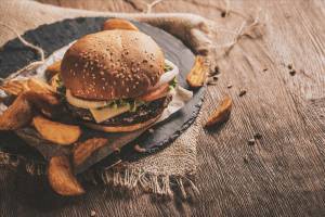 Ein Burger mit Pommes auf einem Holztisch serviert.
