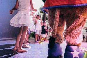 Kinder im Club Marvy tanzen mit einem Charakter in großen Schuhen.
