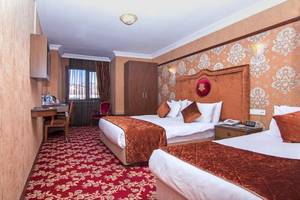 Zwei Betten im Antea Palace Hotel Schlafzimmer mit rotem Teppich und braunen Wandverkleidungen.