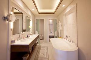 JA Beach Hotel Badezimmer mit Doppelwaschbecken, Badewanne und separater Toilette.