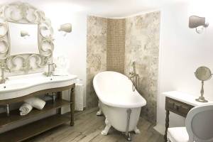 Badezimmer in L'Hostellerie du Moulin mit Badewanne, Waschbecken und dekorativen Wandfliesen.