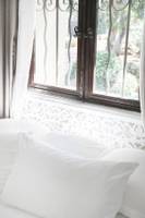 Ein Bett mit weißen Kissen und einem Fenster im Hintergrund im Hotel L'Hostellerie du Moulin