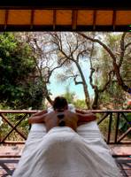 Massage auf Holzterrasse im L'Hostellerie du Moulin mit Blick auf Bäume und Meer