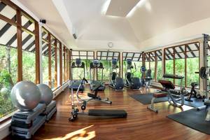 Fitnesscenter im Hotel Sun Siyam Iru Fushi mit Geräten und Blick auf den Garten.