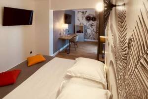 Schlafzimmer im La Lagune Hotel mit Bett, Fernseher und Schreibtisch.