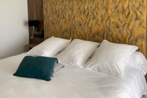 La Lagune Hotelzimmer mit blauem Kissen auf weißem Bett und dekorativer Wand