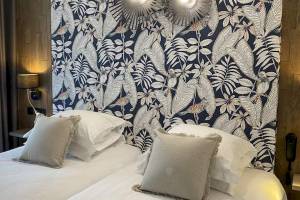 Doppelbett im La Lagune Hotel mit tropischem Wanddesign und Lampen
