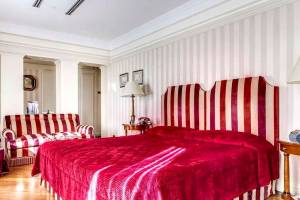 Schlafzimmer im Bettoja Hotel Mediterraneo mit rotem Bett und gestreiften Kopfteil.