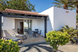 Außenterrasse des Barcelo Fuerteventura Castillo Hotels mit Loungestühlen, Tisch und Palmen im Hintergrund.