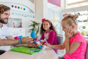 Ein Mitarbeiter des Barcelo Fuerteventura Castillo Hotels spielt mit zwei Kindern an einem Tisch.