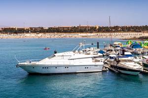 Ein weißes Luxusschiff, das am Hafen neben anderen Booten vor dem Barcelo Fuerteventura Castillo Hotel liegt.