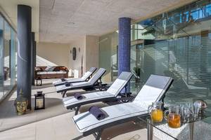 Innenbereich des Barcelo Fuerteventura Castillo Spa mit mehreren weißen Liegen, Glaselementen und einem Buddha-Dekor.