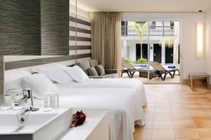 Hotelzimmer im Barcelo Fuerteventura Castillo mit zwei Betten, Wohnzimmerbereich und Terrasse.