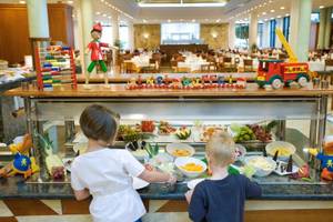 Zwei Kinder stehen vor einem Buffet im Punta Prima Resort & Spa mit verschiedenen Früchten und Dekorationen.