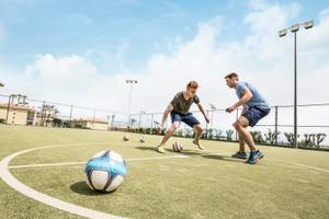 Zwei Männer spielen Fußball auf einem Feld im Punta Prima Resort & Spa.