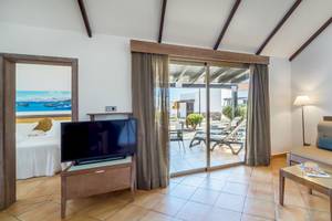 Innenansicht eines Hotelzimmers mit Bett, Fernseher und Balkon.
