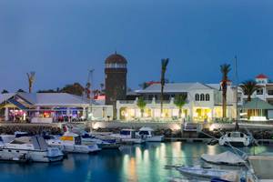 Hafen mit vielen geparkten Booten und dem Barcelo Fuerteventura Castillo Hotel im Hintergrund.