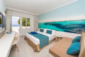 Innenansicht eines Zimmers im Globales Lord Nelson Hotel mit einem großen Bett und einem Ausblick auf das Meer.