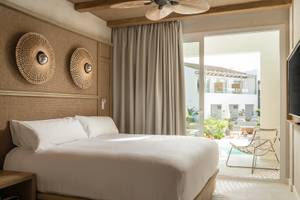 Suite-del-Lago-Zimmer im Lago Resort Menorca mit Bett, Kissen und Ausblick auf einen Pool.