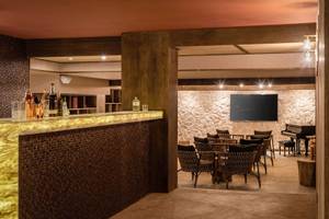 Die Bar des Lago Resort Menorca - Suites del Lago mit einer Theke, Möbeln und einer Fernsehwand.