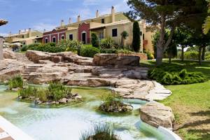 Außenbereich des Grupotel Playa Club mit Wasserfall und Gehweg