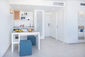 Inneneinrichtung eines Zimmers im Carema Beach Menorca Hotel mit weißen Wänden, einem Tisch, und Küchengeräten.