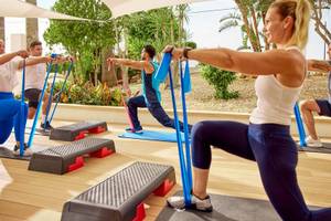 Gruppe von Personen, die Aerobic-Training unter einem Dach auf der Terrasse durchführen.