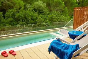 Poolterrasse im Victoria Menorca Hotel mit Blick auf umliegende Bäume.