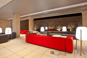 Lounge-Bereich im Seth 55 Santo Tomás Hotel mit roten Sofas und weißen Lampen.