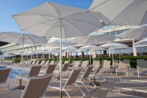 Poolbereich des Seth 55 Santo Tomás Hotels mit vielen weißen Sonnenschirmen und Liegestühlen.