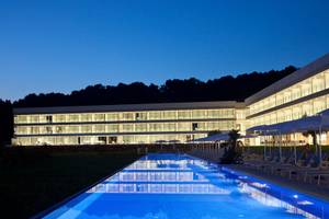 Nachtansicht des Seth 55 Santo Tomás Hotels mit großem Pool und Loungeliegen.