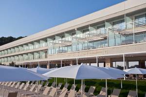 Außenbereich des Seth 55 Santo Tomás Hotels mit vielen weißen Sonnenschirmen und Sonnenliegen